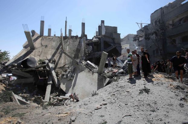 Palestinians gather around the remains of a house which police said was destroyed in an Israeli air strike in Rafah in the southern Gaza Strip