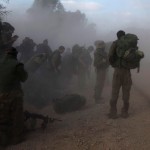 -Israeli soldiers gear up on the side of a road opposite Gaza Strip