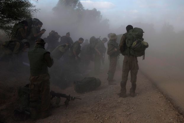 Israeli soldiers gear up on the side of a road opposite Gaza Strip