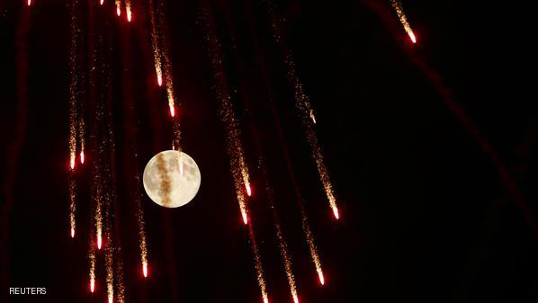 Fireworks streak past in front of the supermoon outside the town of Mosta, celebrating the feast of its patron saint, in central Malta