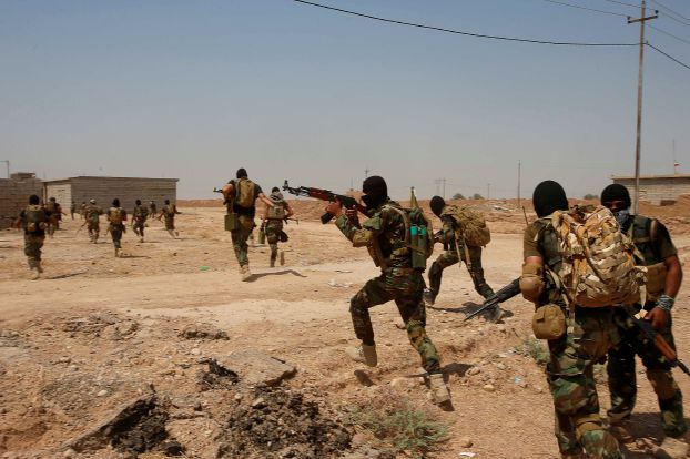 Asaib Ahl al-Haq Shi'ite militia fighters from the south of Iraq run during a mission to take control of Sulaiman Pek village from Islamist State militants, in the northwest of Tikrit city