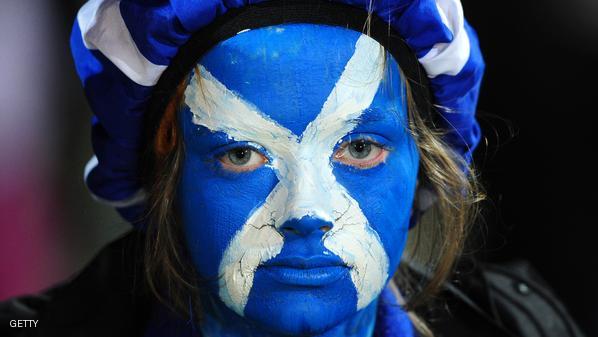 A Scottish fan with a painted face looks