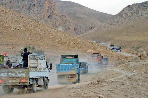 Displaced people from the Yazidi religious minority, fleeing violence from forces loyal to the Islamic State in Sinjar town, ride trucks as they are evacuated from Mount Sinjar