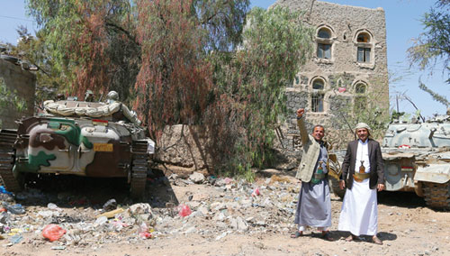 متمردان بجانب دبابتين استولت عليهما جماعة الحوثي