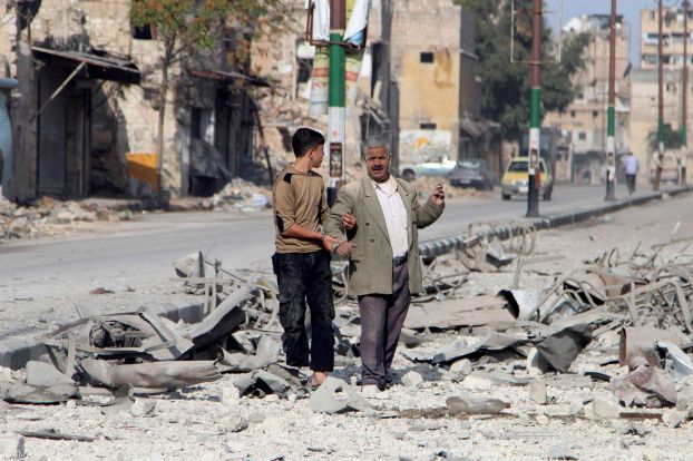 Residents inspect damage after what activists said were barrel bombs dropped by warplanes loyal to Syria's President Bashar al-Assad in Old Aleppo