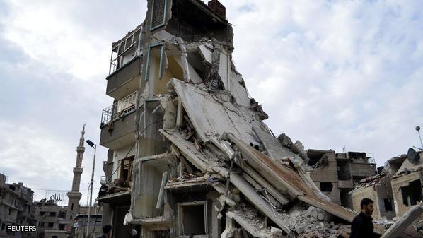 Men walk past damaged buildings after what activists said were air strikes by forces loyal to Syria's President Bashar al-Assad in the Douma neighborhood of Damascus