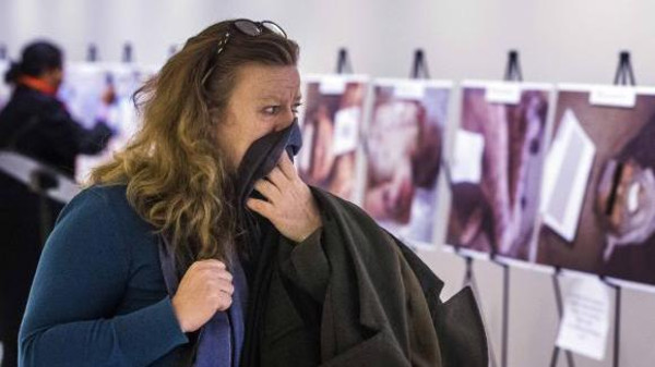 A woman reacts as she looks at a gruesome collection of images of dead bodies taken by a photographer, who has been identified by the code name "Caesar," at the United Nations Headquarters in New Yor