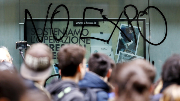 Protesters march past a window of a bank painted with the words "No Expo" during a rally against Expo 2015 in Milan