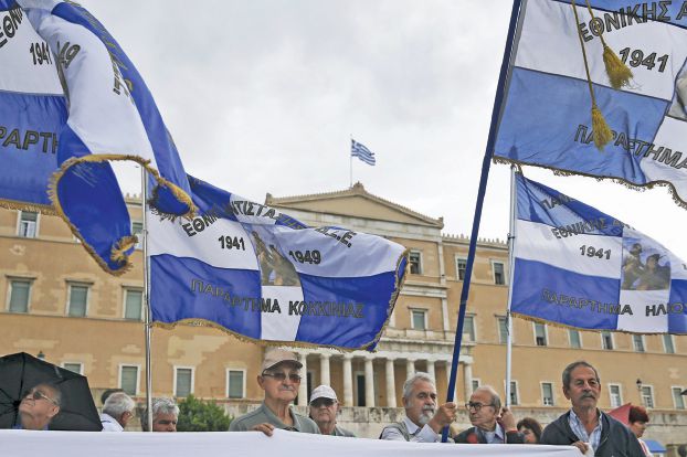 Protesters wave Greek national flags with depictions from the Greek World War II resistance during a demonstration in front of the parliament building in Athens