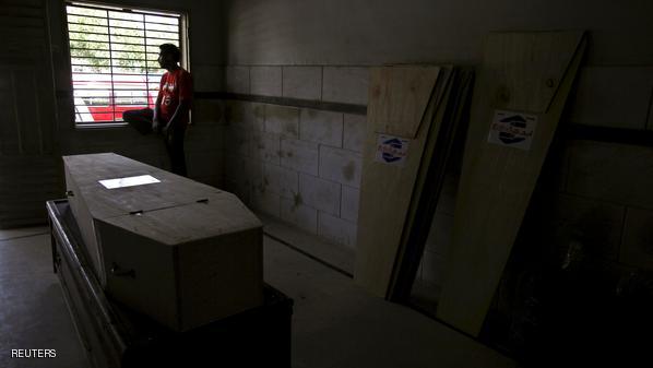 A volunteer sits beside a window, while waiting for the relatives of a deceased who died due to intense hot weather to collect the body, at Edhi Foundation morgue in Karachi