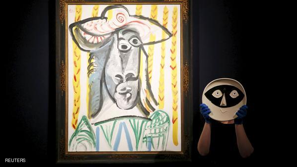 File photo of a member of staff posing with a ceramic plate next to "Tete" both by Picasso at Christie's auction house in London