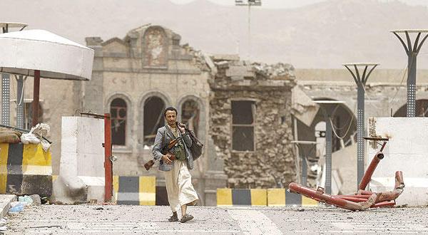 مسلح موال للحوثيين يسير أمس أمام مجمع وزارة الدفاع